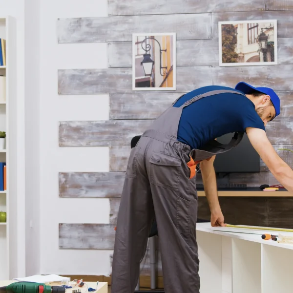 trabajador-montaje-muebles-pie-instrucciones-lectura-usando-cinta-metrica-herramientas-trabajador